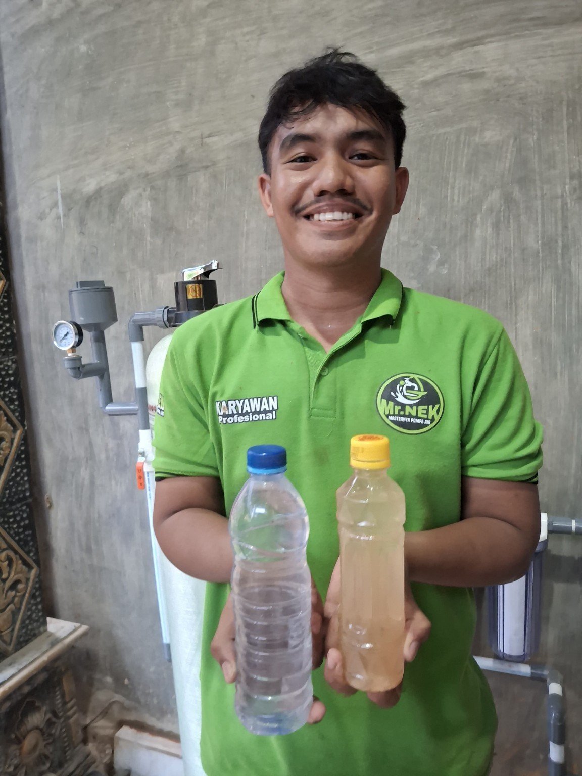 Anggota tim menunjukkan dua sampel air saat kegiatan pemasangan.